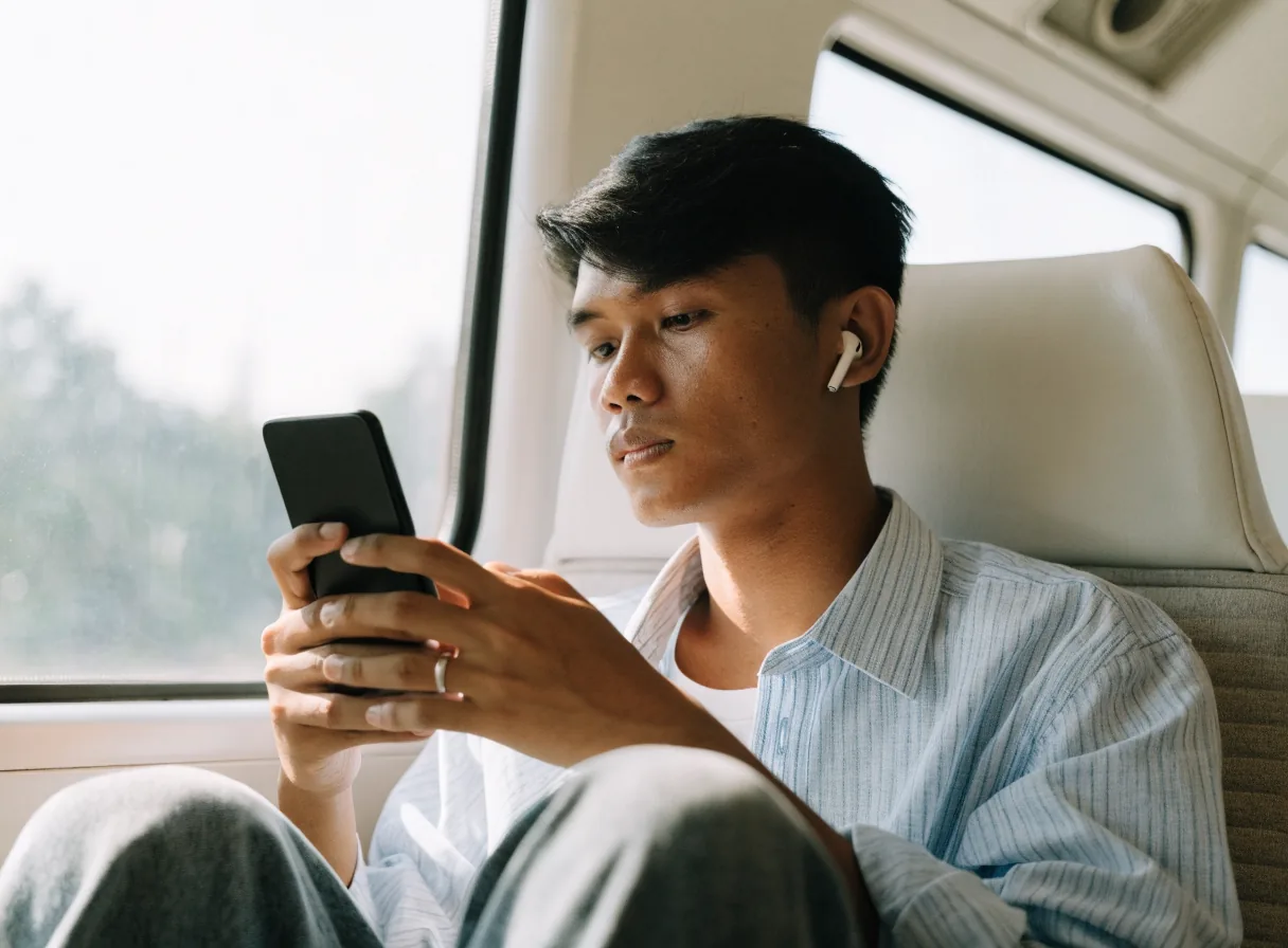 Pemuda mendengarkan musik dengan earbuds di dalam kereta